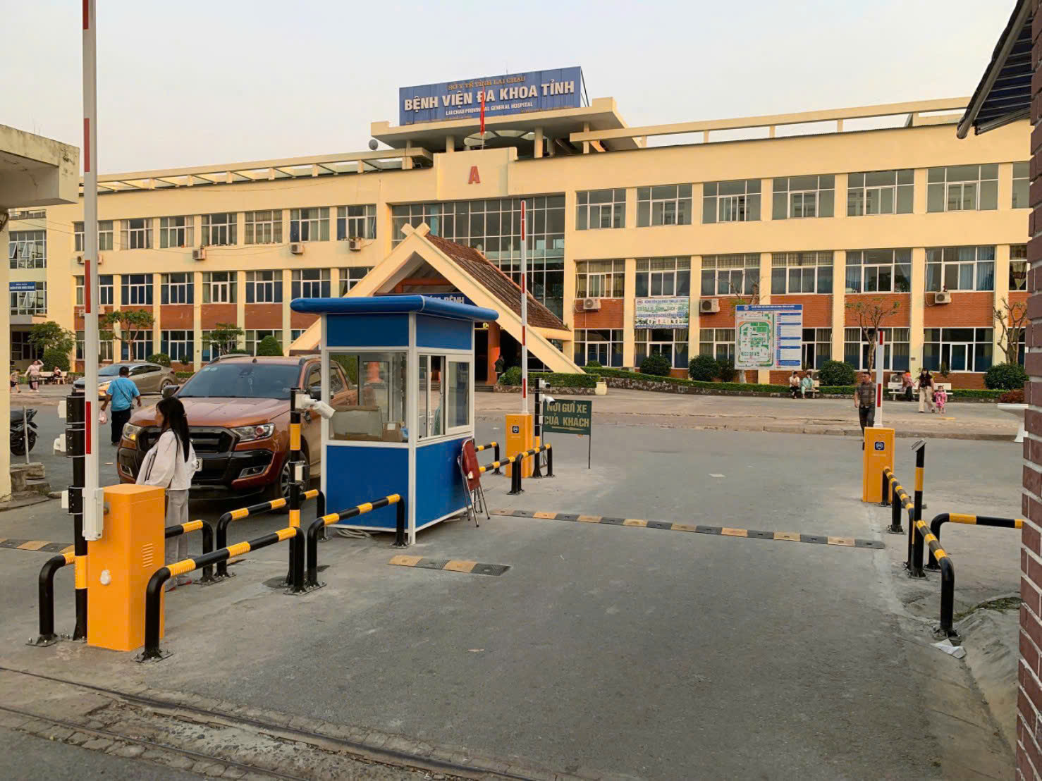 Cổng bãi giữ xe tự động với barie và chốt bảo vệ trước tòa nhà bệnh viện đa khoa